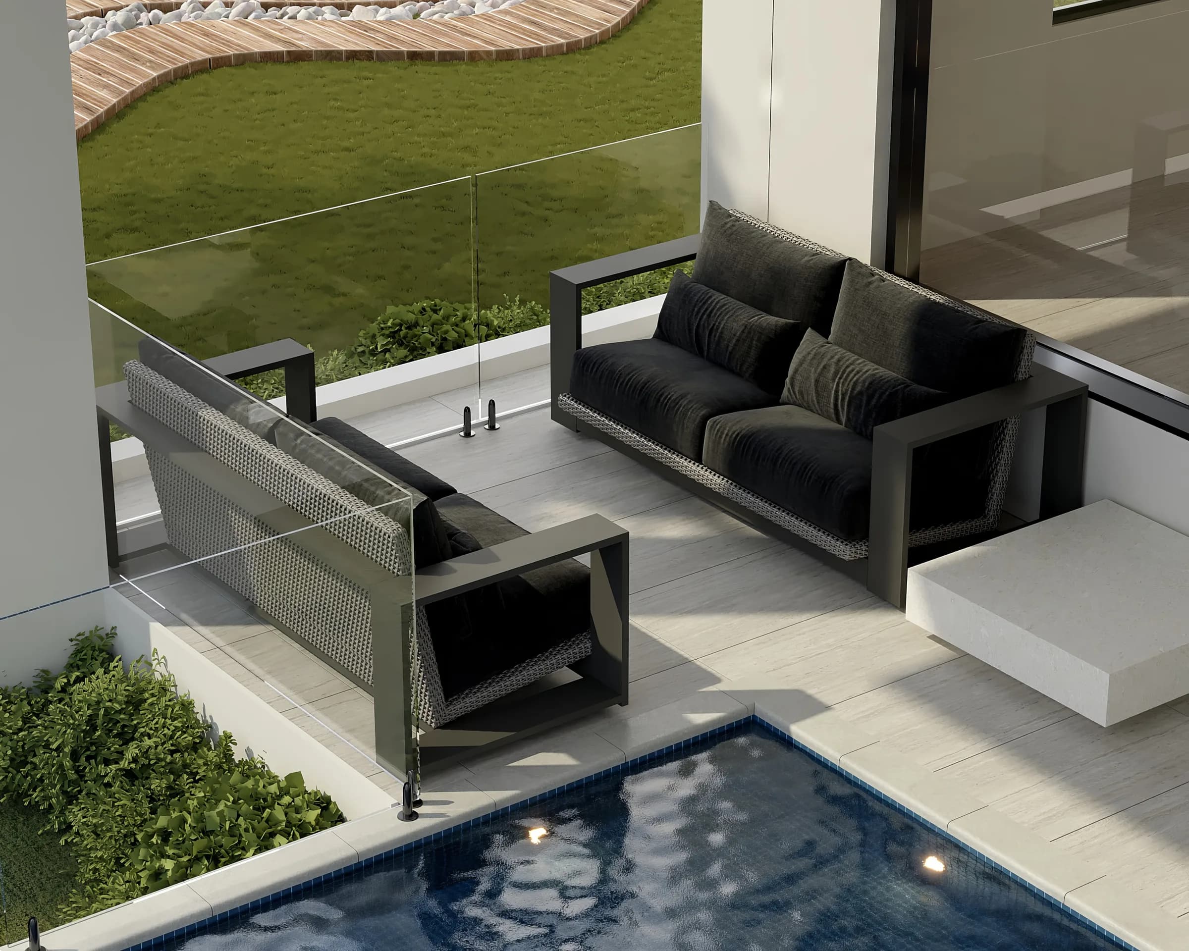 Poolside terrace with black woven lounge seating, pale stone paving and frameless glass overlooking the lawn