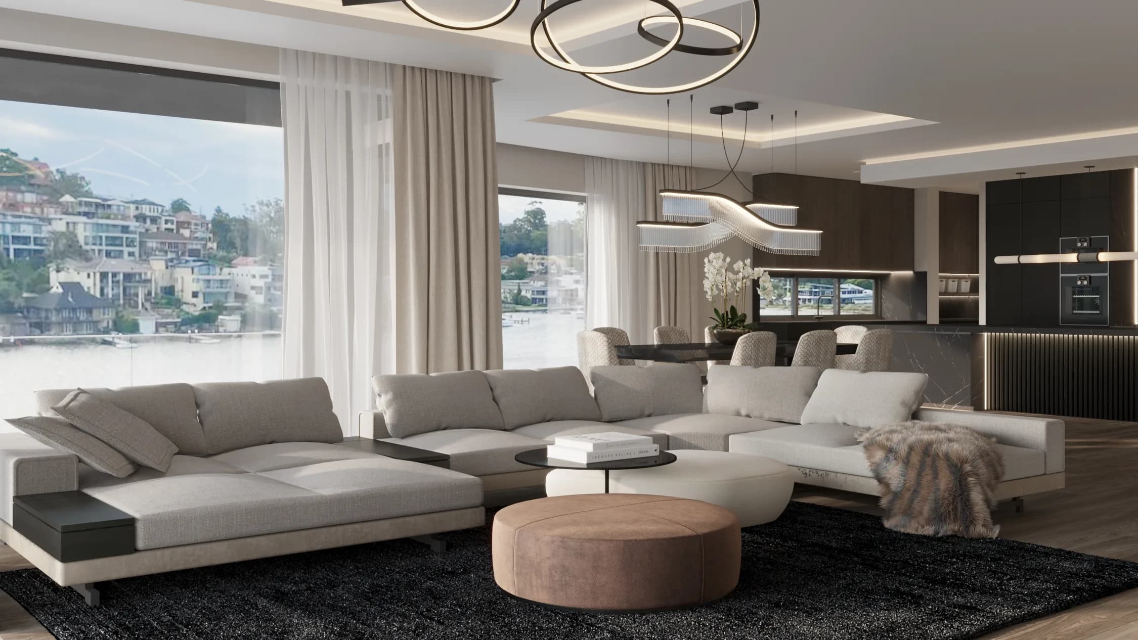 Open-plan living room with a pale sectional on a black rug, sculptural ring lights and waterfront views