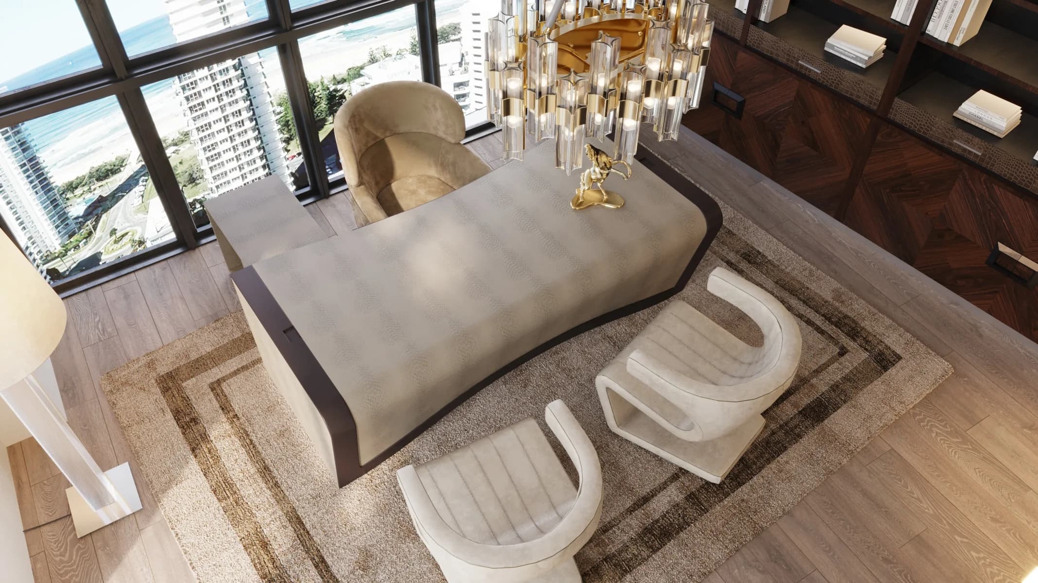 Overhead view of a sculptural cream desk and chairs beneath a crystal chandelier beside ocean-facing windows