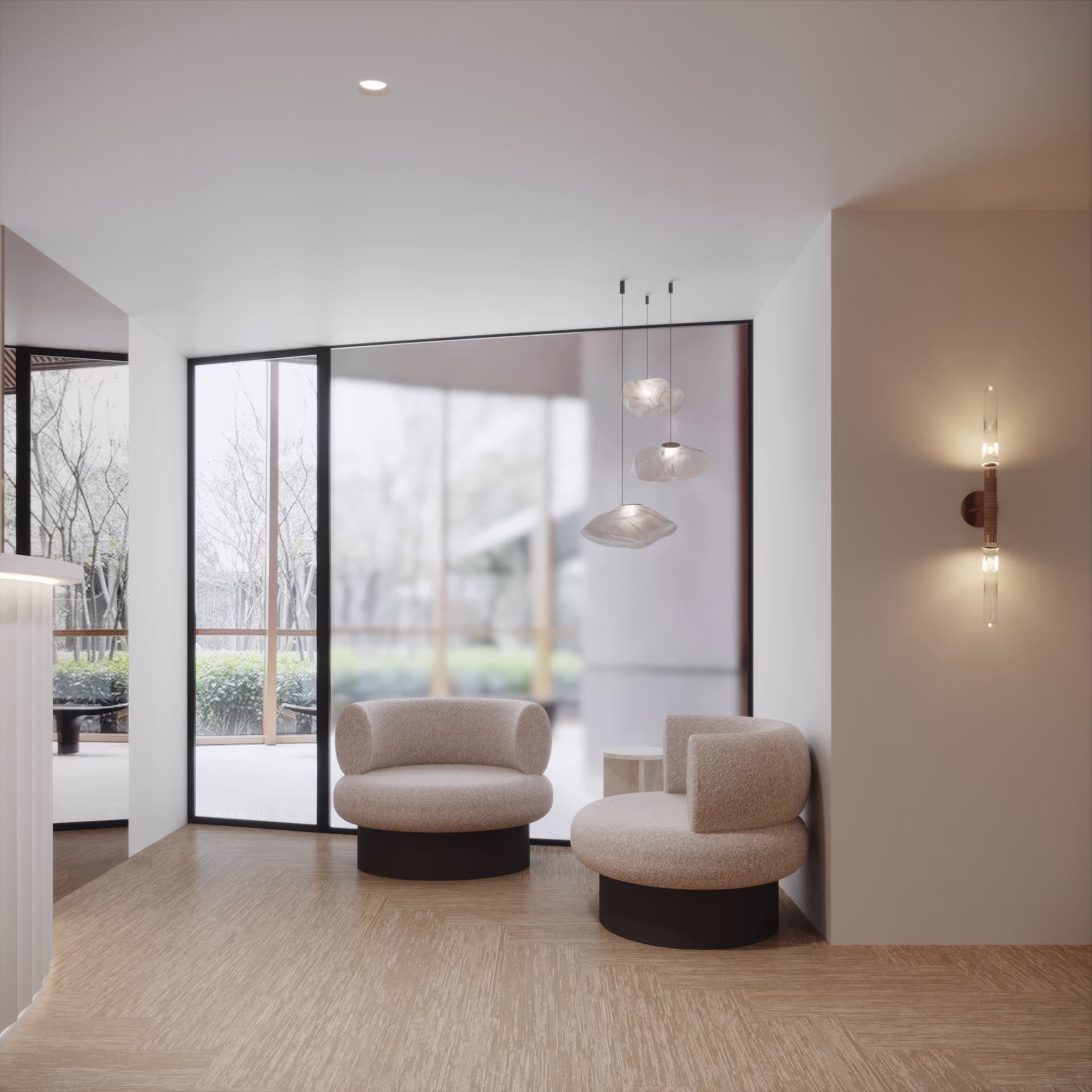 Waiting nook with two rounded cream chairs on dark plinths, pale herringbone flooring and clustered glass pendants