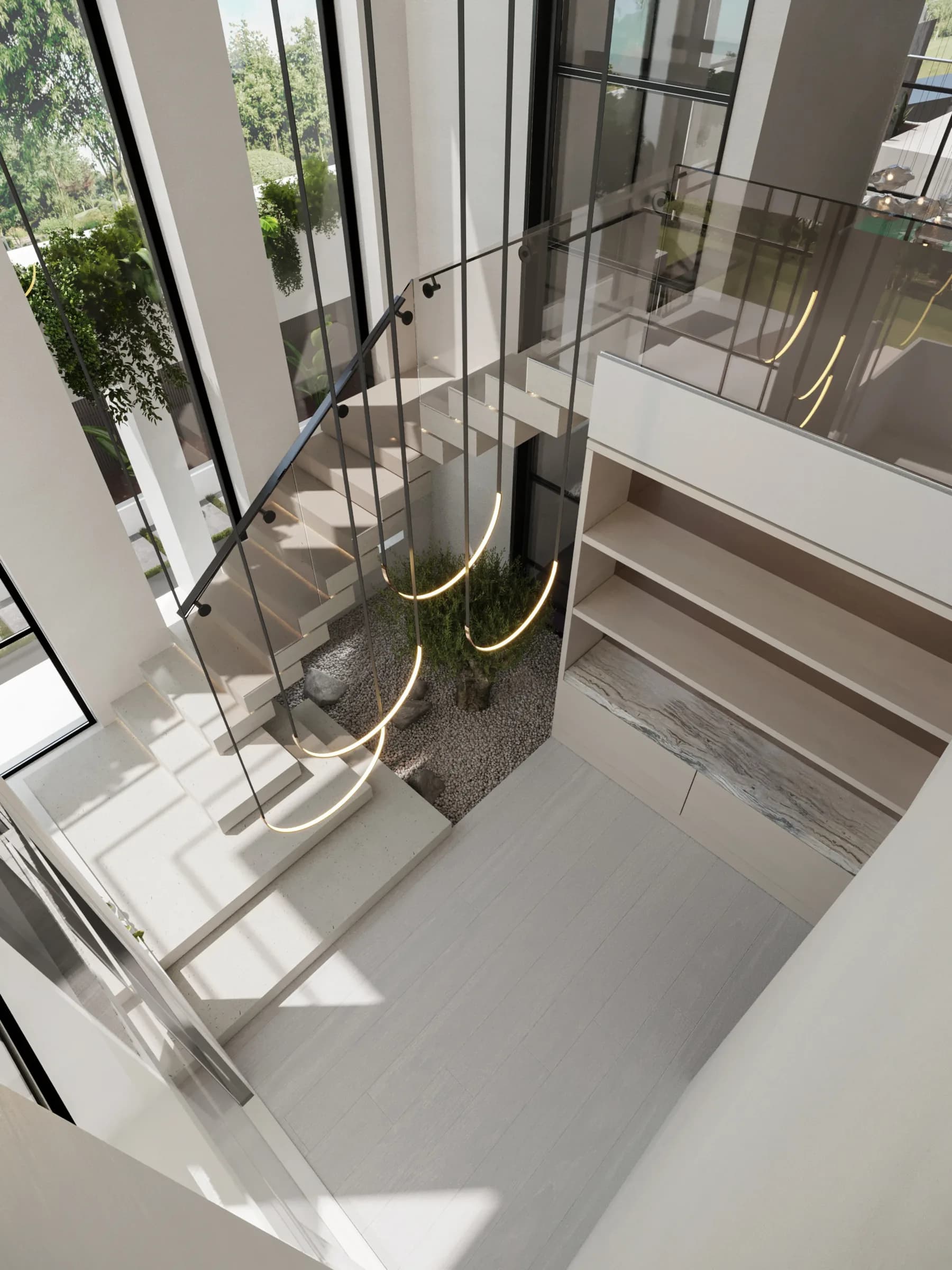 Upper-level view over a glazed stair void, floating white steps, looping pendants and a pebble-set indoor tree