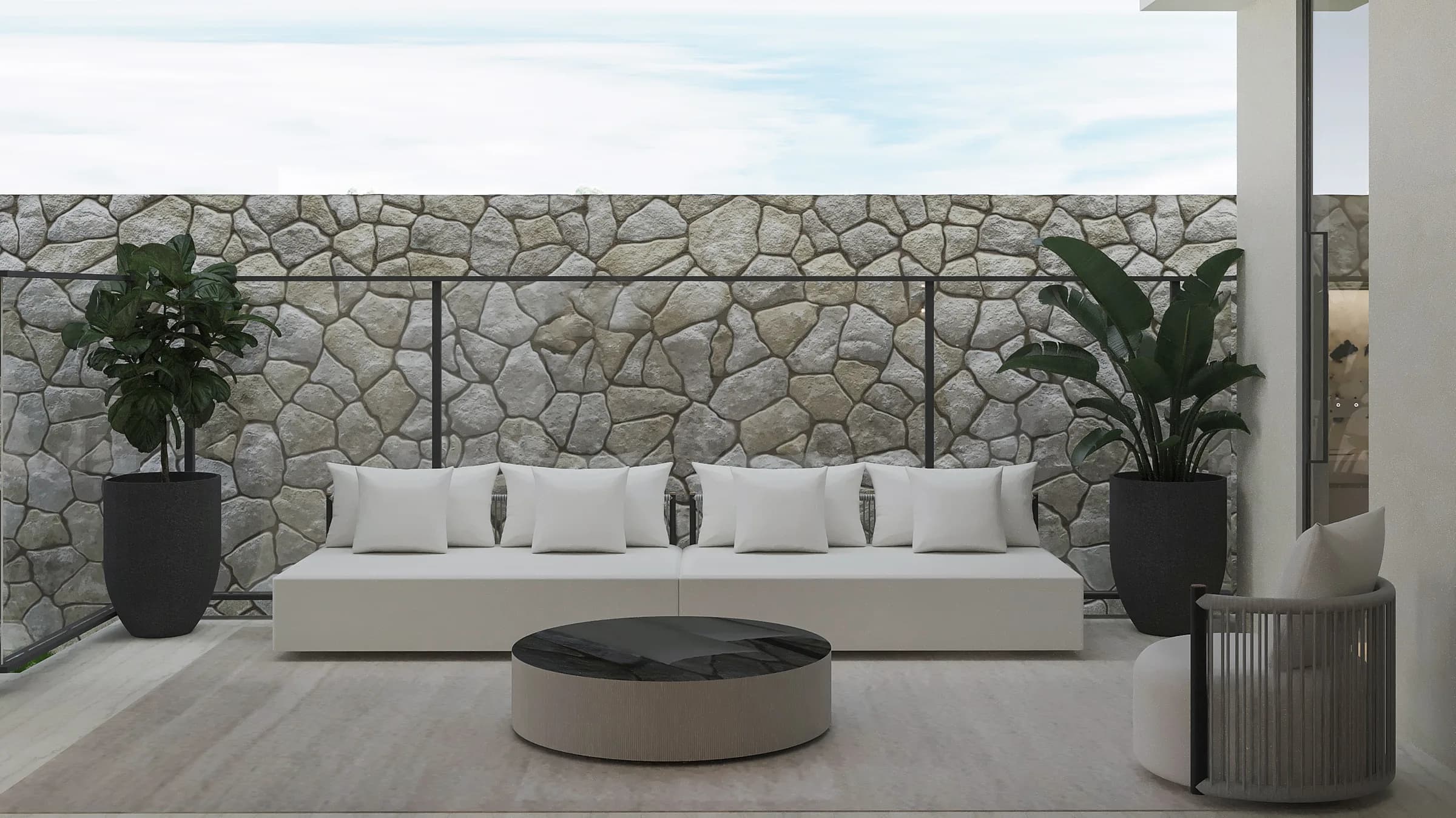Covered terrace with white cushioned seating, a black stone coffee table and rugged stone boundary wall