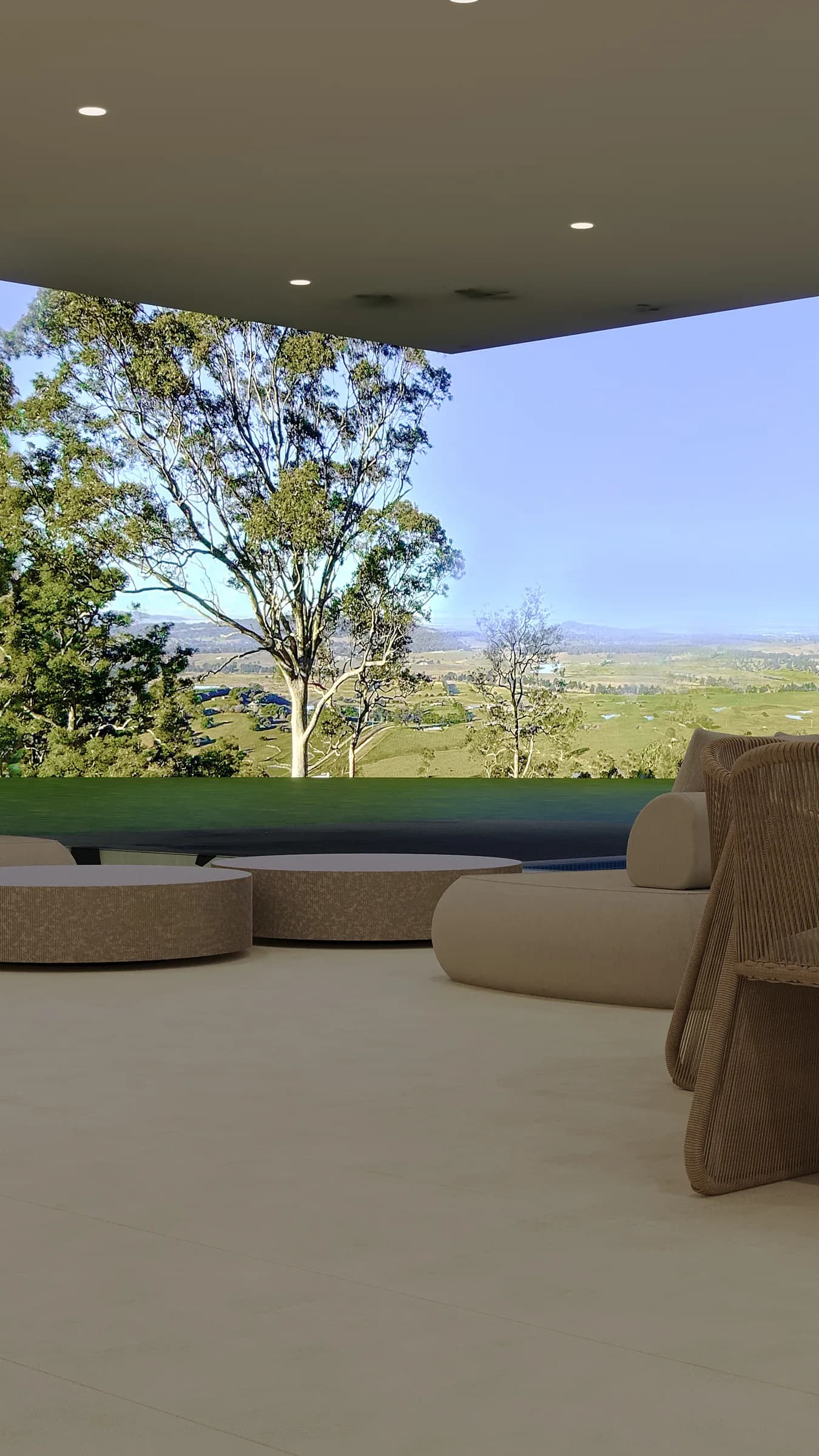 Covered terrace with cream upholstery, woven seating and round low tables beside an infinity pool and sweeping valley view