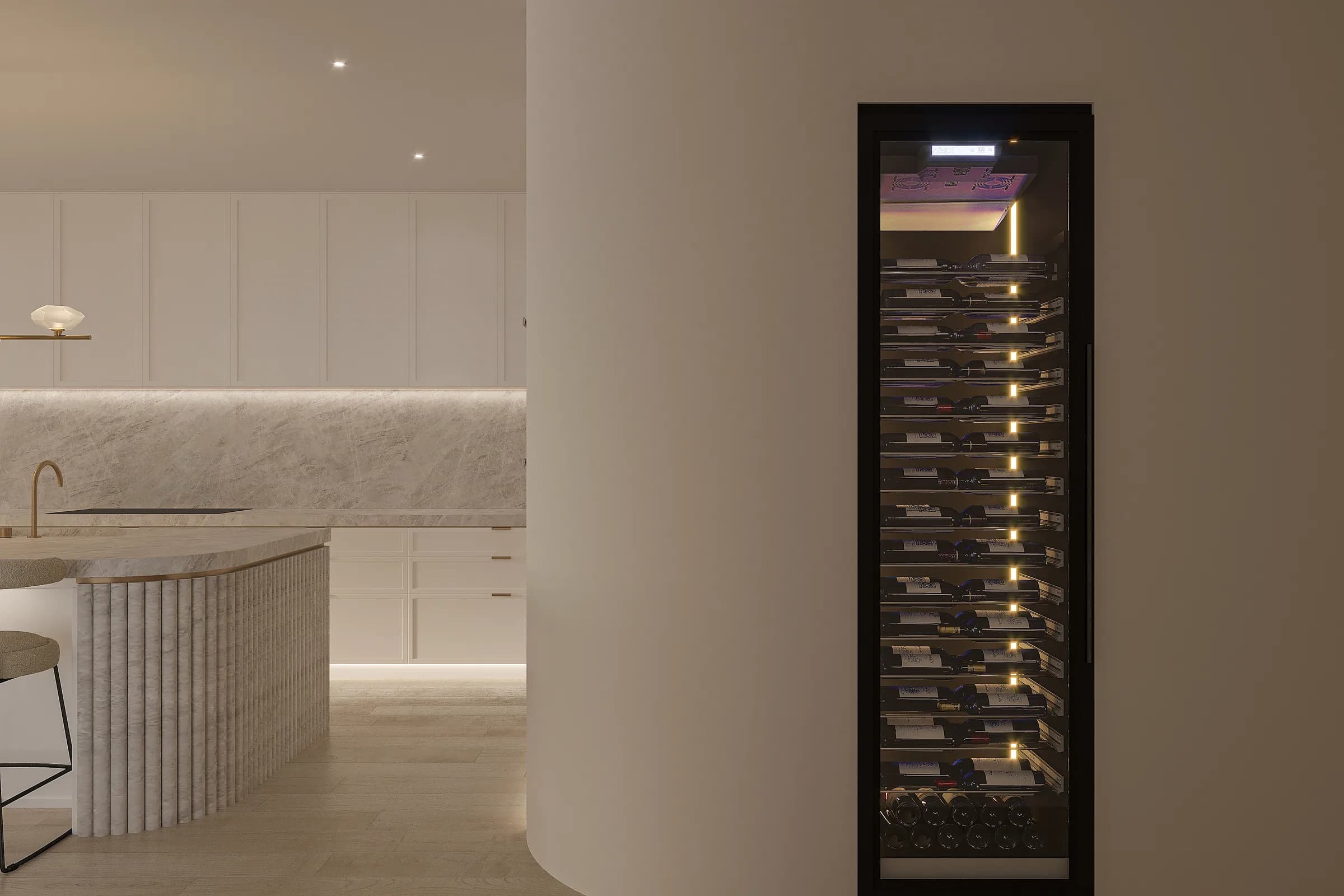 Illuminated glass-fronted wine cabinet set into rounded joinery beside the pale stone and brass kitchen