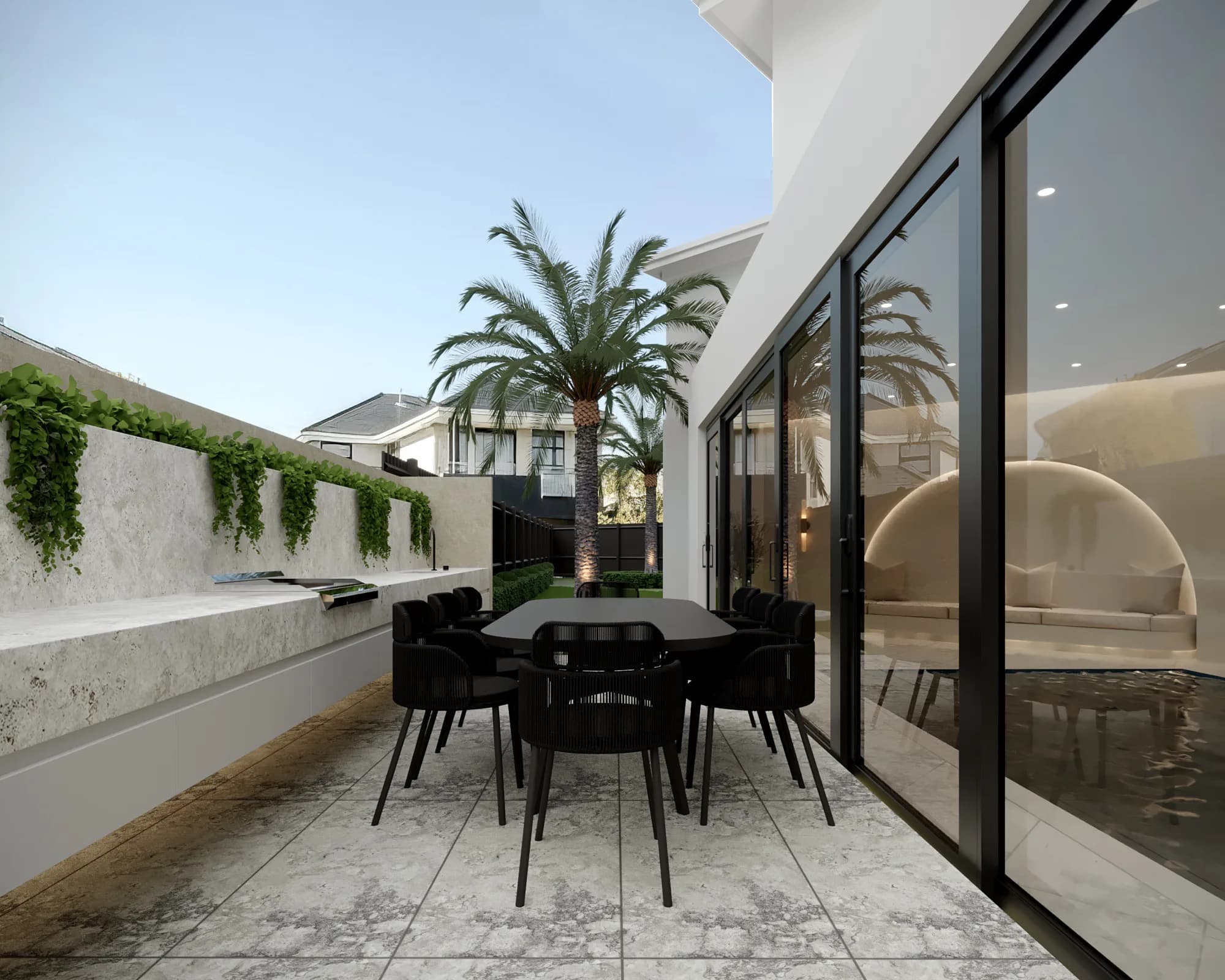 Outdoor dining terrace with a black table, pale stone kitchen bench, glass doors and a palm-lined garden