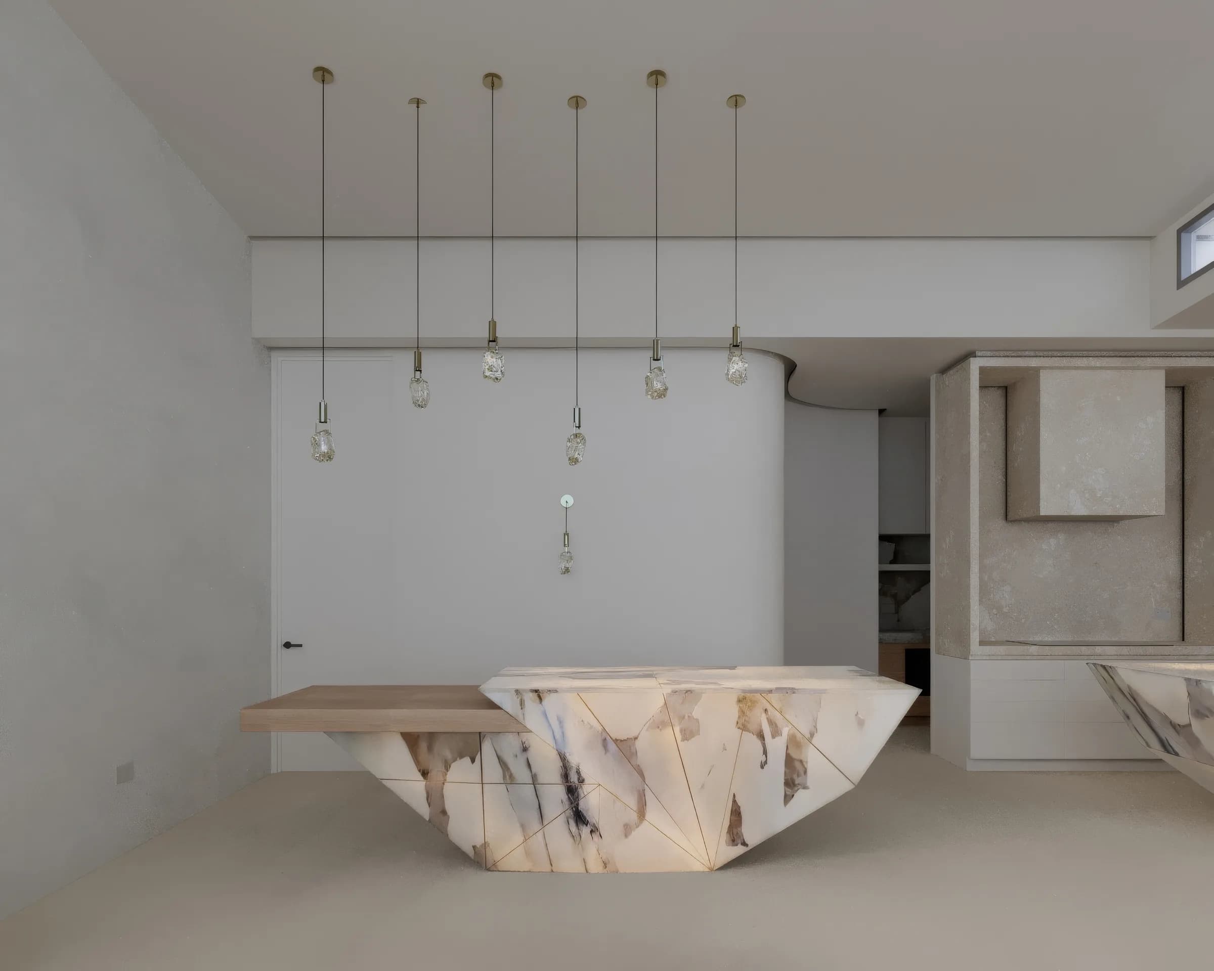 Sculptural white kitchen with a veined stone island, stone range hood and pendant cluster beneath an unlit cove